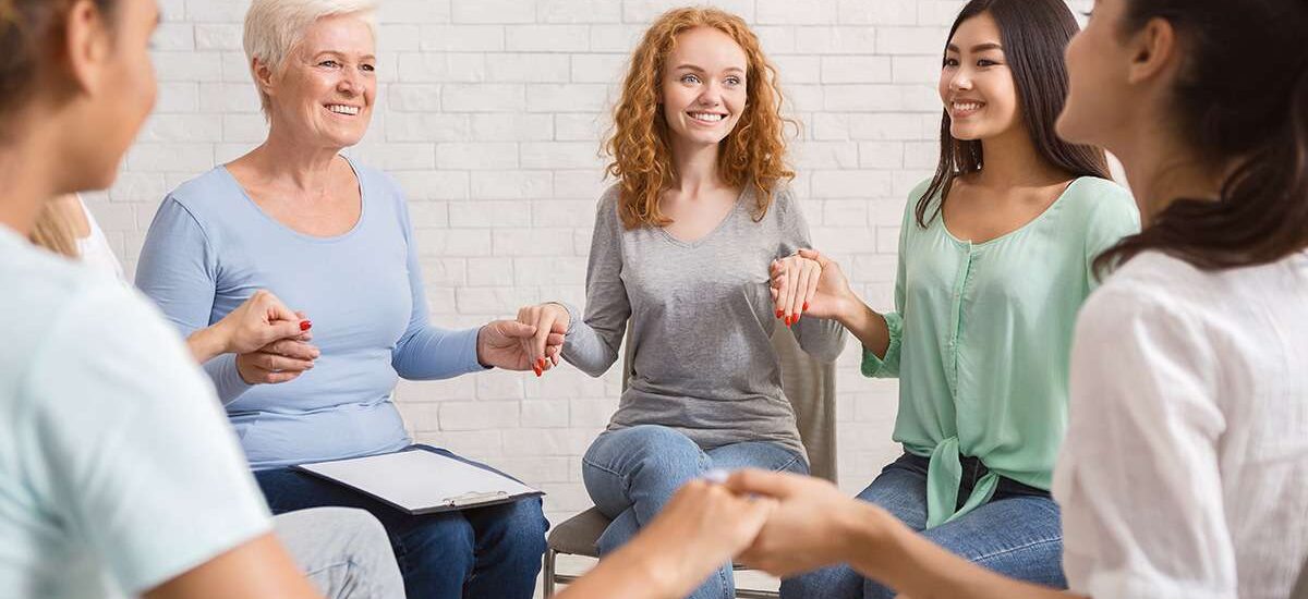 group-therapy-session-women-only-hold-hands-smiling